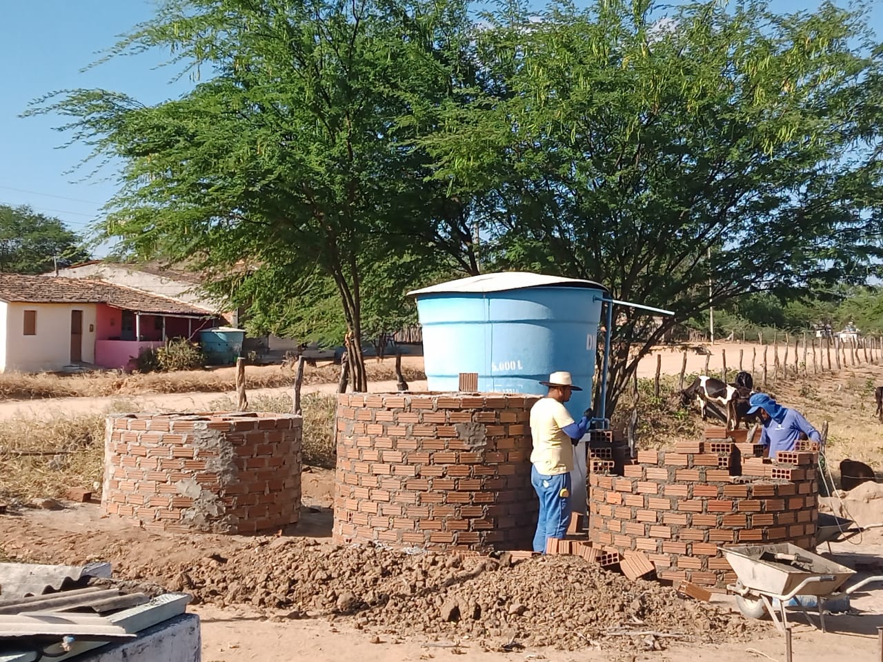 Foto apresenta a etapa de construção de três caixas d'água em zona rural.