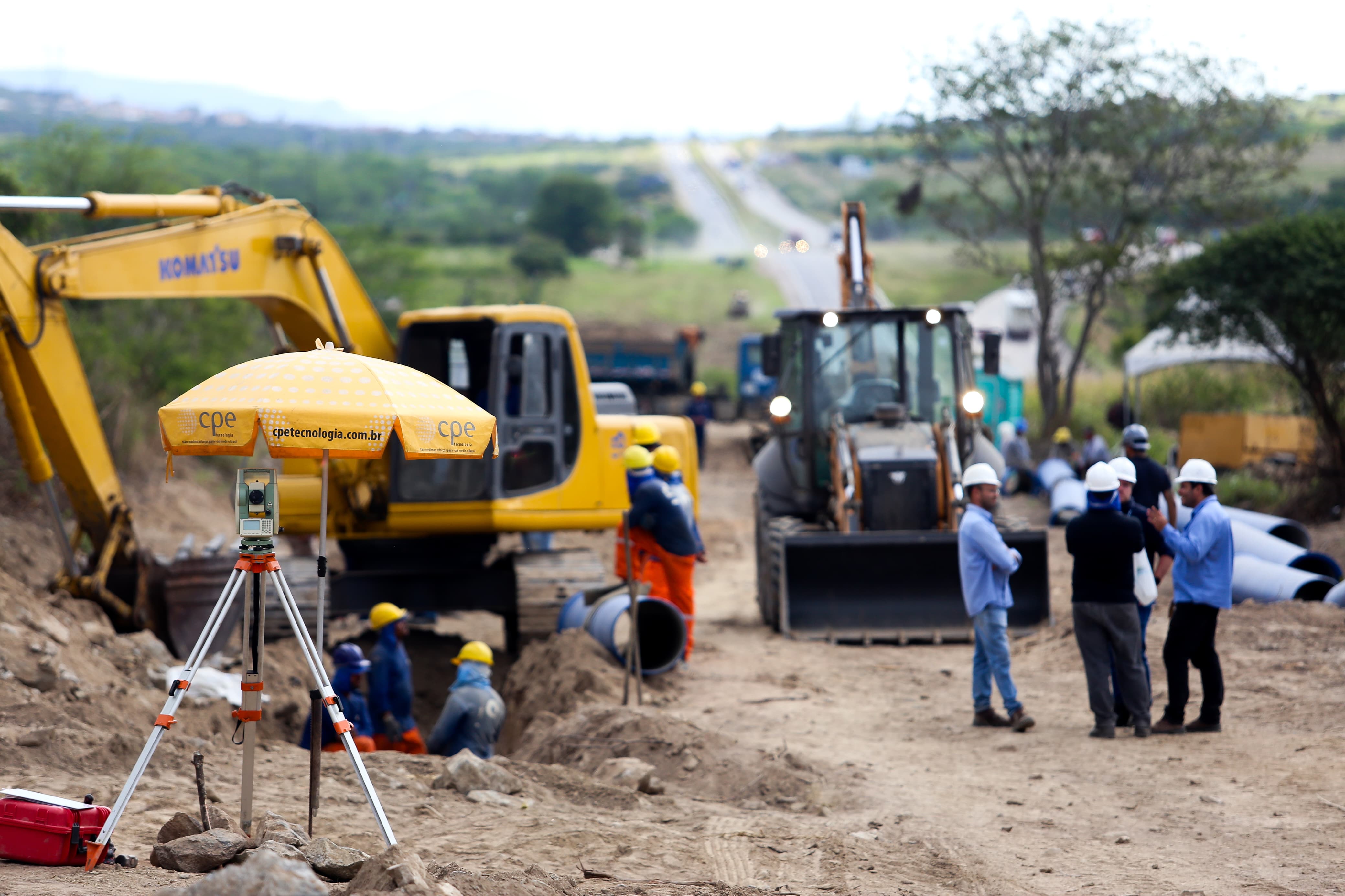 Foto da obra da Adutora do Agreste em Bezerros-PE. A foto apresenta tirada à distância de área onde há máquinas e homens trabalhando. 